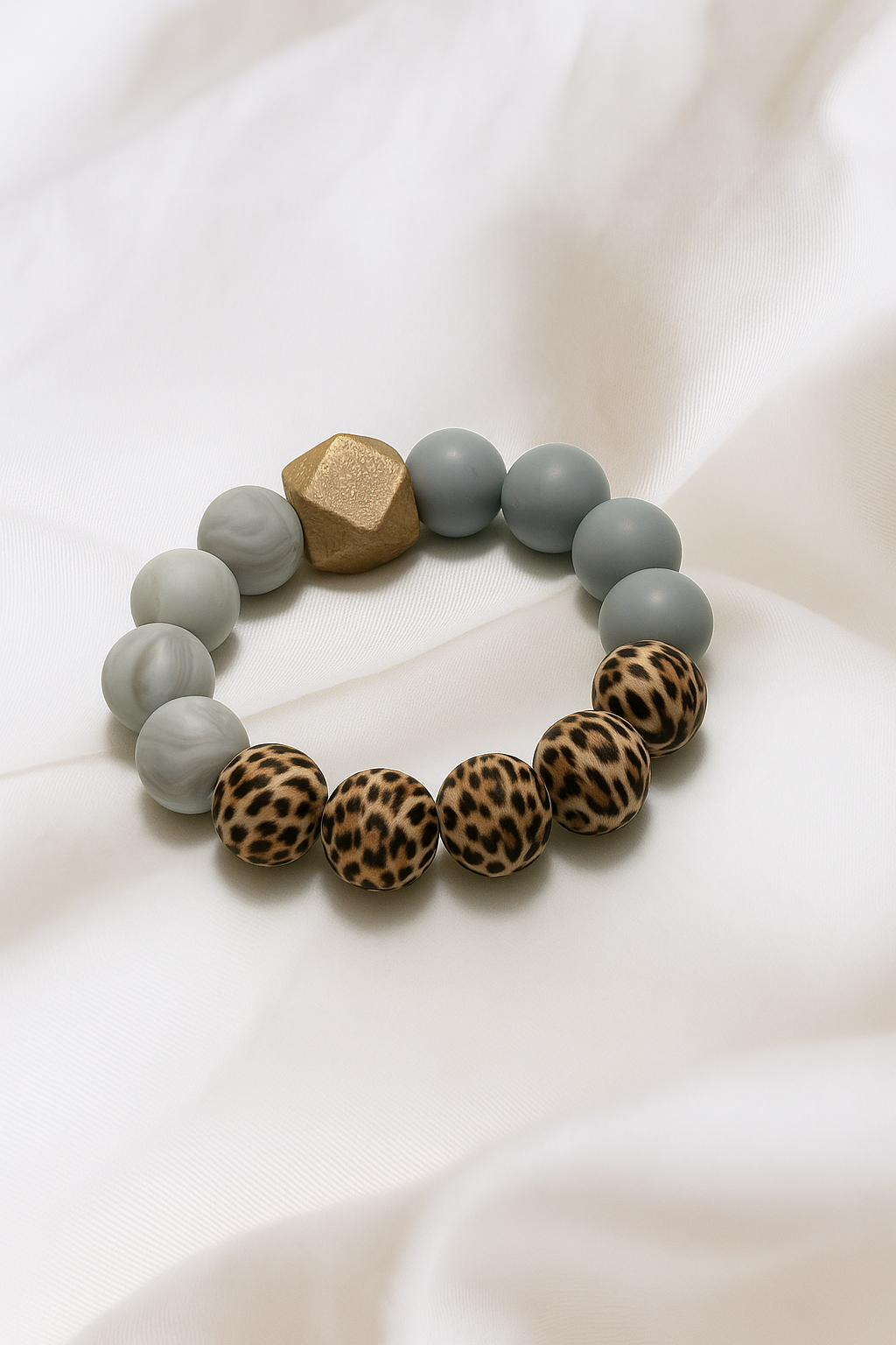 Bracelet with gray beads and leopard print beads on a white fabric background